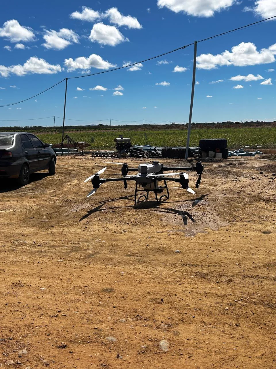 Drone agrícola parado no terreno em uma área rural.